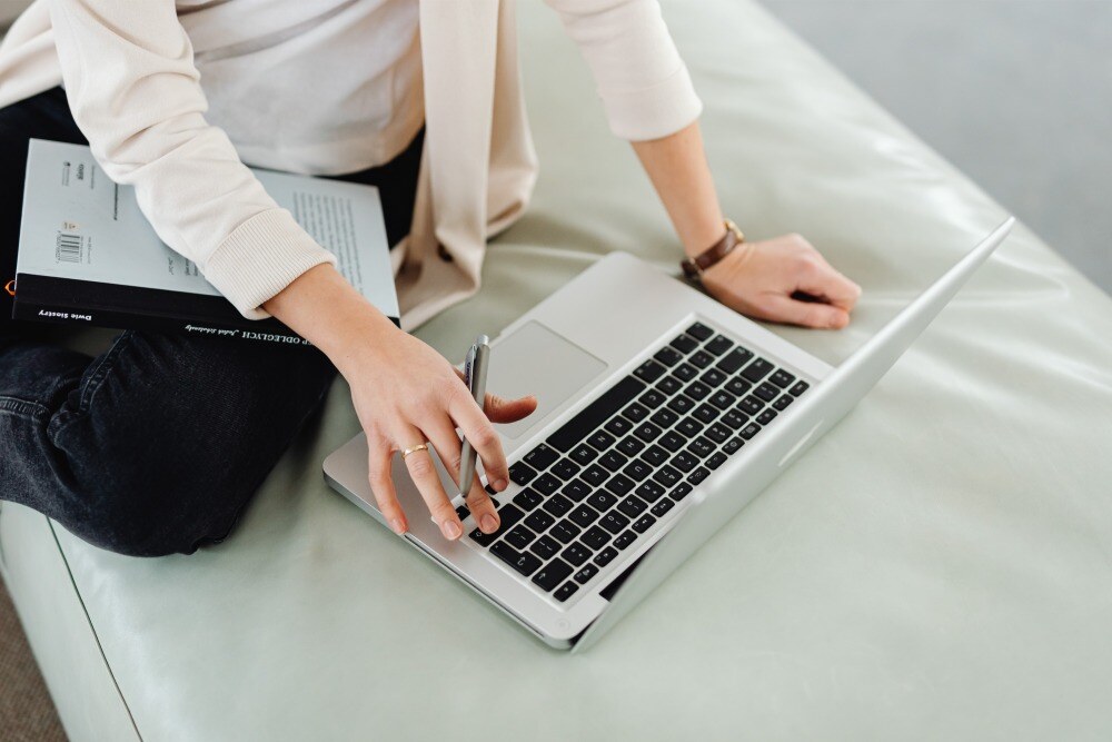 person with book working on laptop